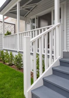 a white porch with blue steps and green grass