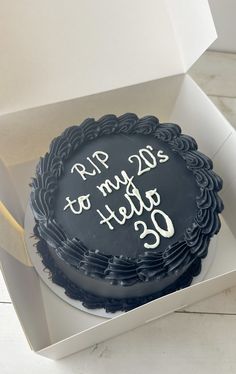 a black cake in a white box with writing on it