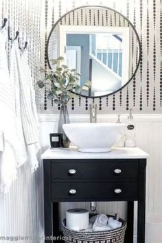 a black and white bathroom with a round mirror above the sink, towel rack on the wall