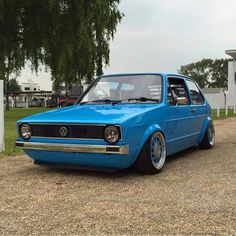 a blue car parked on top of a gravel road