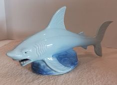 This vintage porcelain ceramic figurine features a "ferocious" shark with a blue glazed finish.  The figurine stands at approx  5" tall, approx 9" long and approx 3" wide. Made in Brazil, it is a unique addition to any animal figurine collection or a great decorative piece for any occasion.   This vintage shark figurine is in good condition with age-related wear. There is a worn spot on the tip of his tail fin. As shown in the pictures. Please see all of the photos for condition. There are no chips or cracks. Ceramic Shark, Figurine Collection, Ceramic Figurine, Ceramic Figurines, Animal Figurines, Porcelain Ceramics, Made In Brazil, Vintage Porcelain, Decorative Pieces