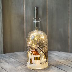 a lighted bottle with a house on it