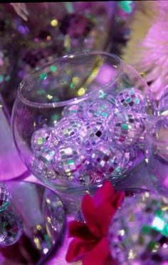 some glass goblets are sitting on a table with purple and green glitters