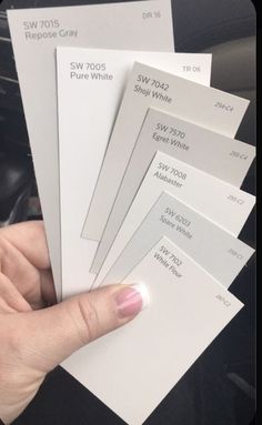 a person holding five different white samples in their hand, with the price listed on them