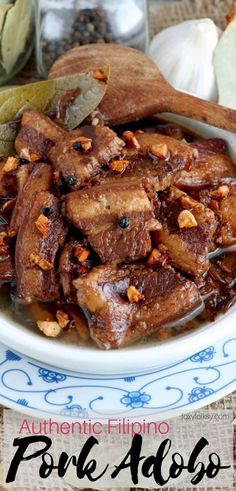 a bowl filled with meat and nuts on top of a table next to some bread