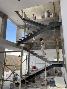 two men are standing on scaffolding in an unfinished building