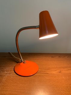 an orange desk lamp sitting on top of a wooden table