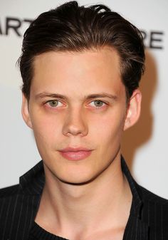 a close up of a person wearing a black shirt and looking at the camera with a serious look on his face