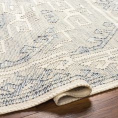 an area rug with blue and white designs on the bottom, laying on top of a wooden floor