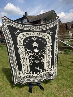 a large black and white quilt sitting on top of a green grass covered field next to a house