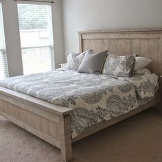 a bedroom with a large bed and two windows