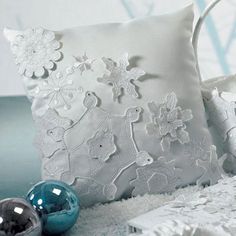 a white pillow and some ornaments on a bed with blue balls in the foreground