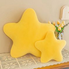 a yellow star pillow sitting on top of a table next to a vase with flowers