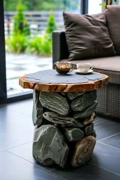 a coffee table made out of rocks with a bowl on it and a cup sitting on top