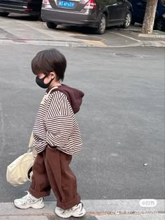 a young boy wearing a face mask crossing the street