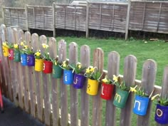 colorful flower pots are hanging on a fence