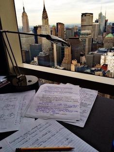 some papers are sitting on top of a desk in front of a cityscape