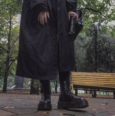 a man in black coat and boots holding an umbrella