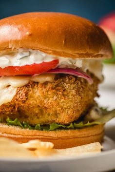 a fried chicken sandwich on a bun with lettuce, tomato and mayonnaise