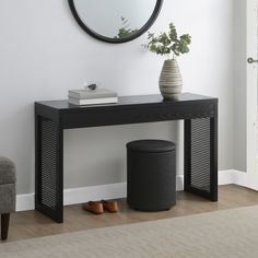 a black console table with a round mirror above it