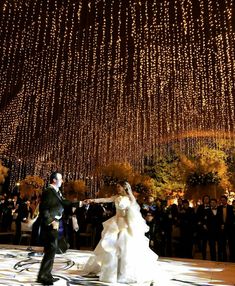 the bride and groom are dancing under lights