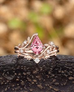 a pink diamond ring sitting on top of a rock