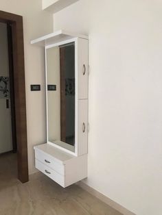 a white cabinet sitting next to a mirror on top of a wooden floor in a room