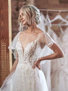 a woman standing in front of some wedding dresses