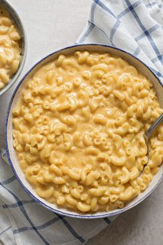 two bowls filled with macaroni and cheese on top of a blue checkered cloth