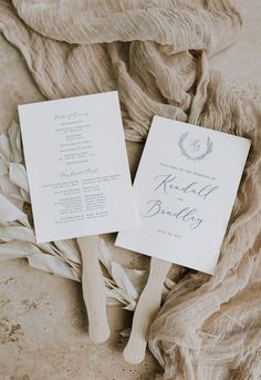 two wedding programs laying on top of a pile of cloth and wood skewers