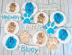 decorated cookies with blue and white frosting on a wooden table next to paw prints