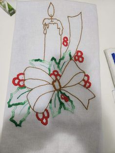 a white towel with red and green flowers on it next to a toothbrush holder