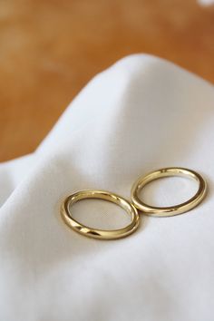 two gold rings sitting on top of a white cloth