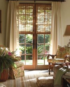 a living room filled with furniture and a large window covered in blinds next to a door