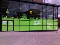 a large green building with many windows and signs on the side of it's wall