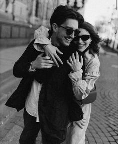 black and white photograph of a man hugging a woman on the street with buildings in the background