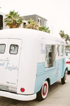 an ice cream truck is parked on the side of the road with palm trees in the background