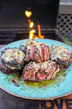 grilled steaks on a blue plate with flames in the background