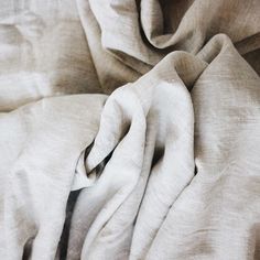 an unmade bed with white sheets and pillows