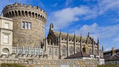 an old castle like building with a clock tower on it's side and people walking around