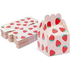 a pink box with strawberries on it next to a stack of paper napkins