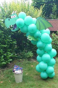 a dragon balloon arch in the shape of a bunch of balloons with a trash can underneath it