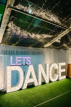 a sign that says let's dance on it in front of a stage with lights