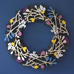 a wreath made out of paper with flowers and leaves hanging on the side of it