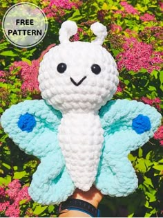 a crocheted white and blue butterfly sitting on top of a person's hand