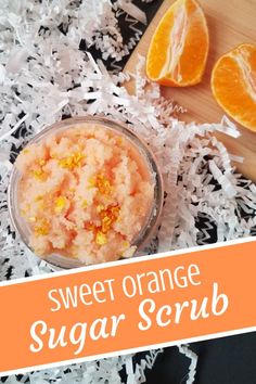 sweet orange sugar scrub in a glass bowl with shredded white paper around it and an orange slice on the side