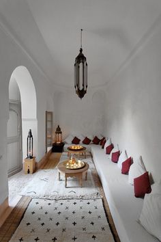 a living room filled with lots of white furniture and red pillows on top of it