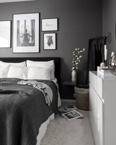 a bedroom with gray walls and pictures on the wall above the bed in black and white