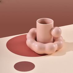 a pink vase sitting on top of a white table next to two brown circles in the background