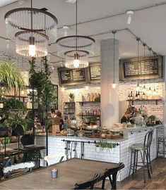 the inside of a restaurant with tables, chairs and plants hanging from the ceiling above